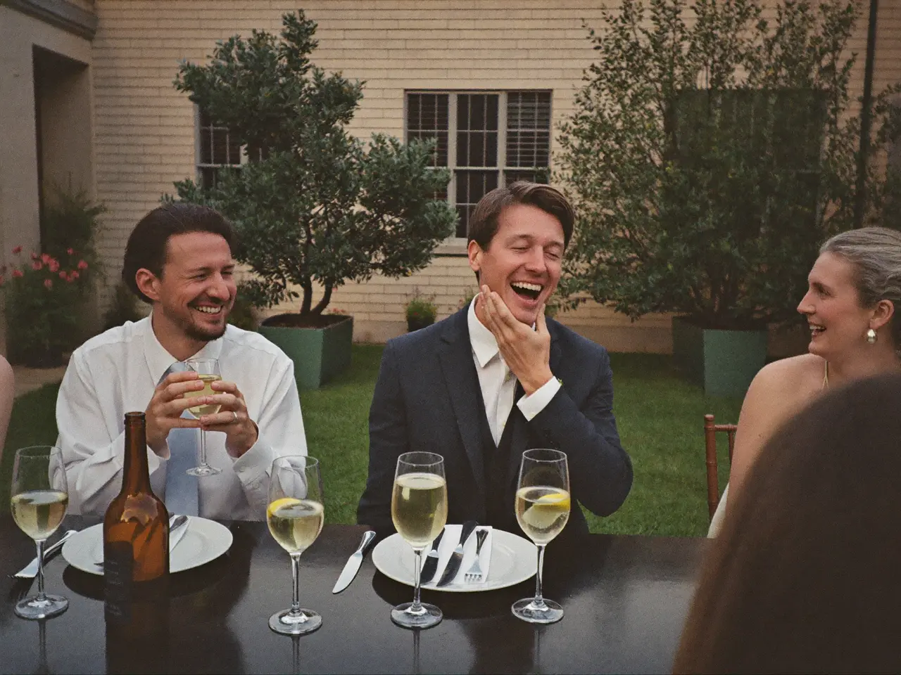 The groom laughing with friends in the courtyard