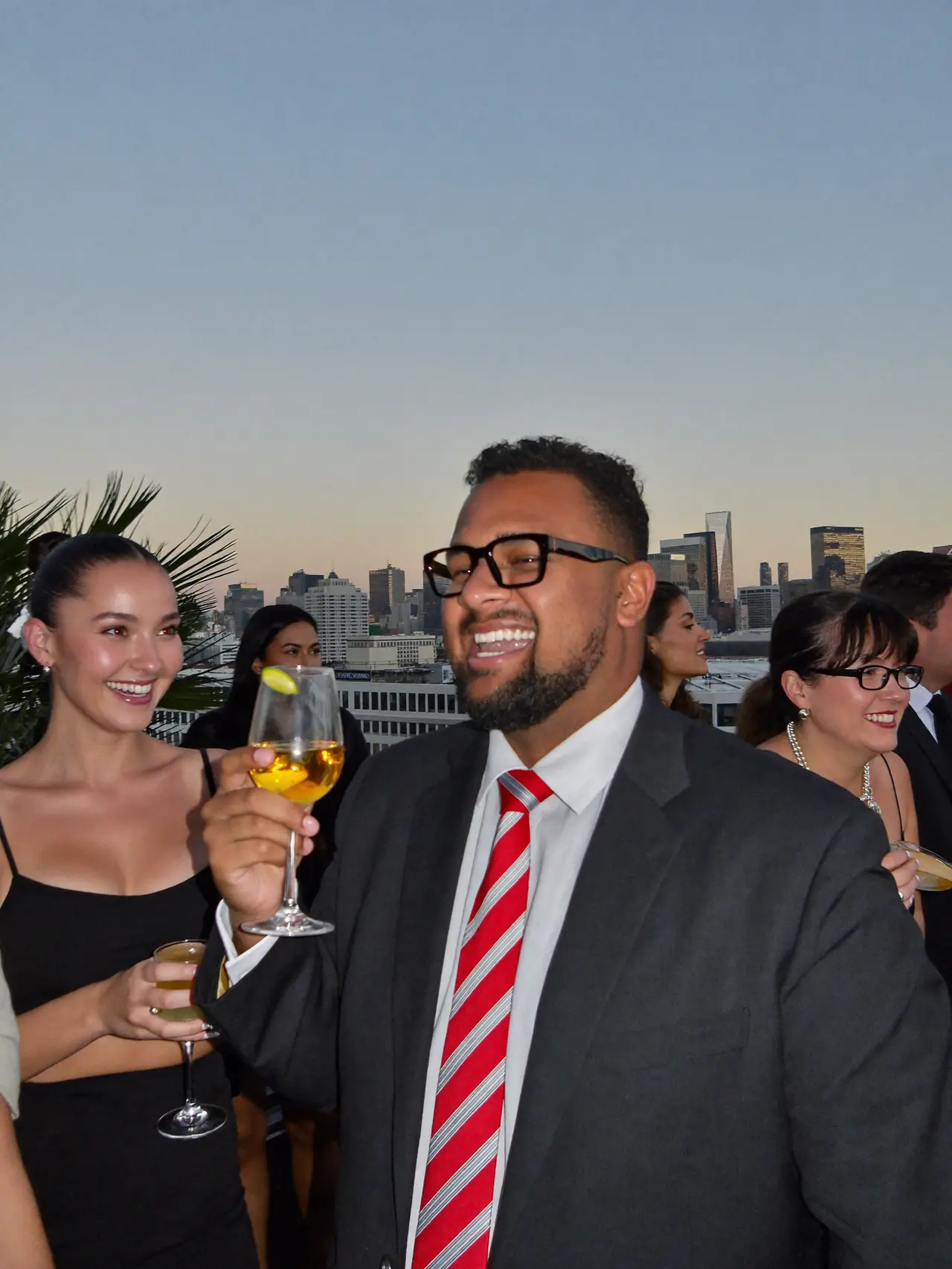 Coworkers at a rooftop company party at dusk