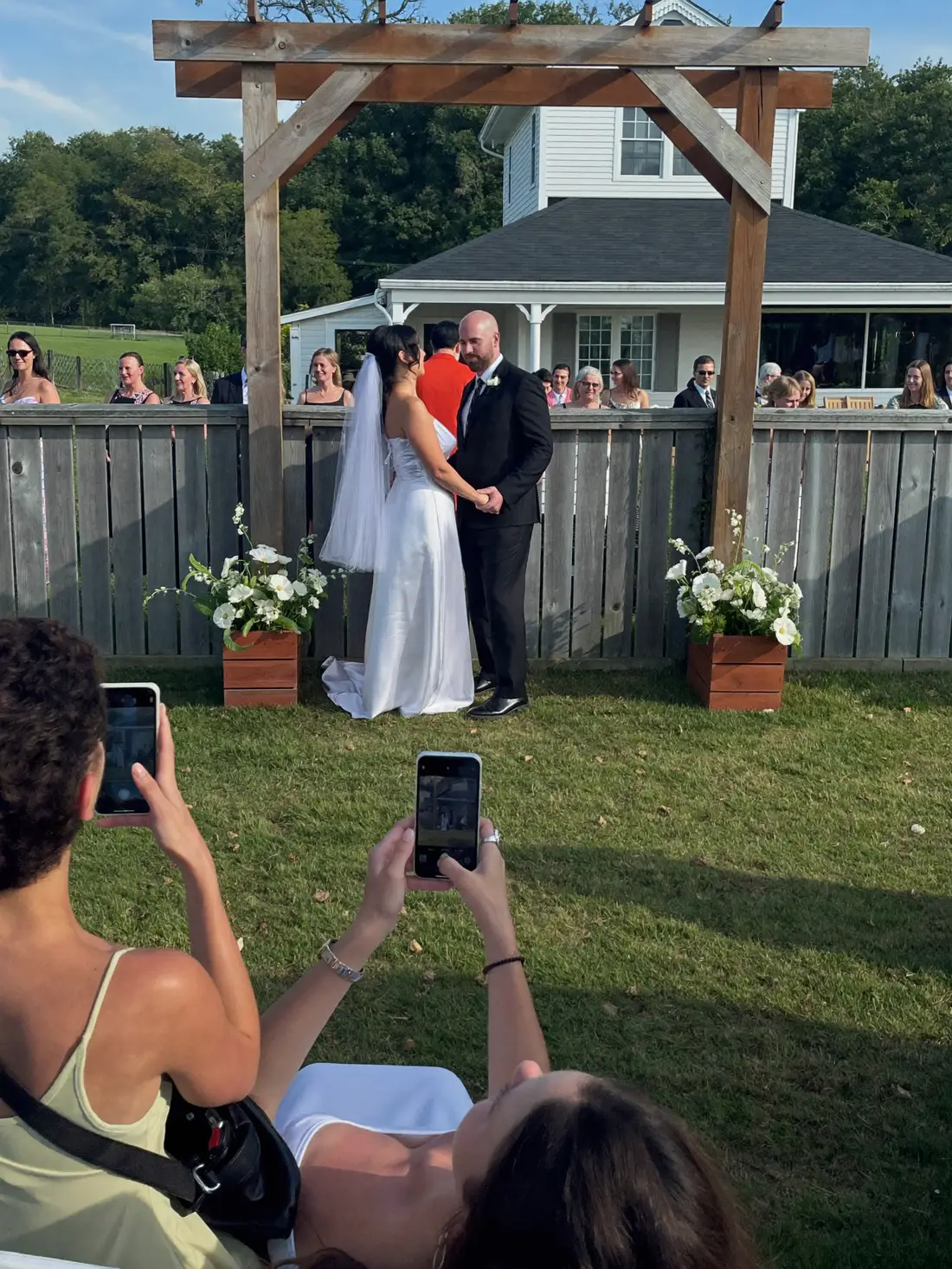 Backyard ceremony under a wooden arch